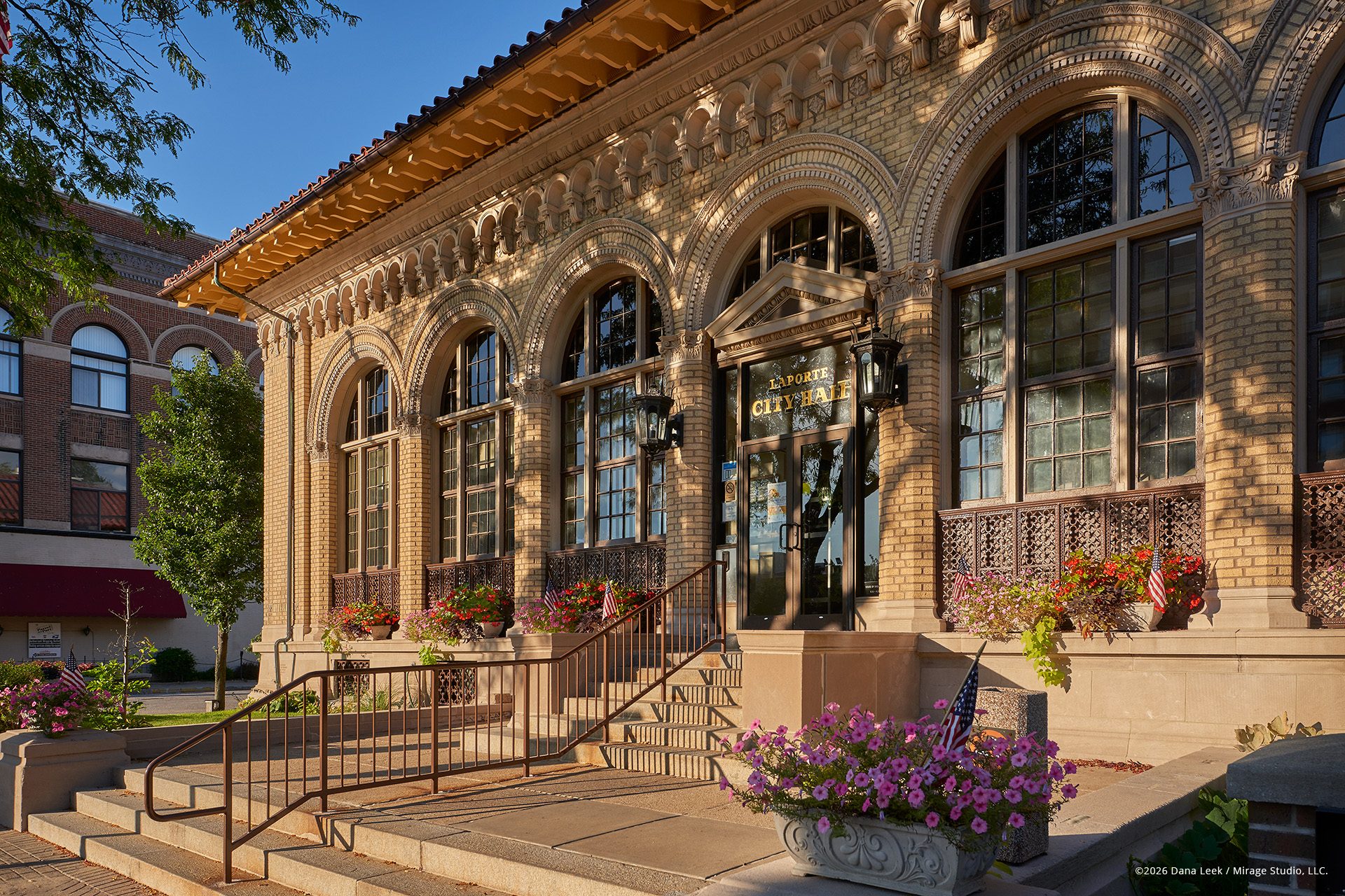 La Porte City Hall’s historic façade catches warm evening light, highlighting its rich masonry arches, ornate detailing, and patriotic summer plantings along Michigan Avenue in downtown La Porte, Indiana.