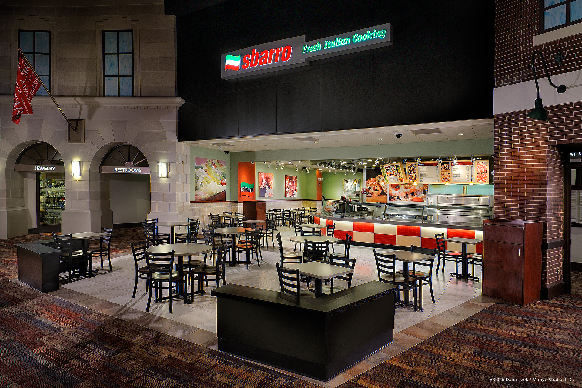 Sbarro “Fresh Italian Cooking” food‑court restaurant with open counter, menu boards, and dining area set within a themed mall streetscape.