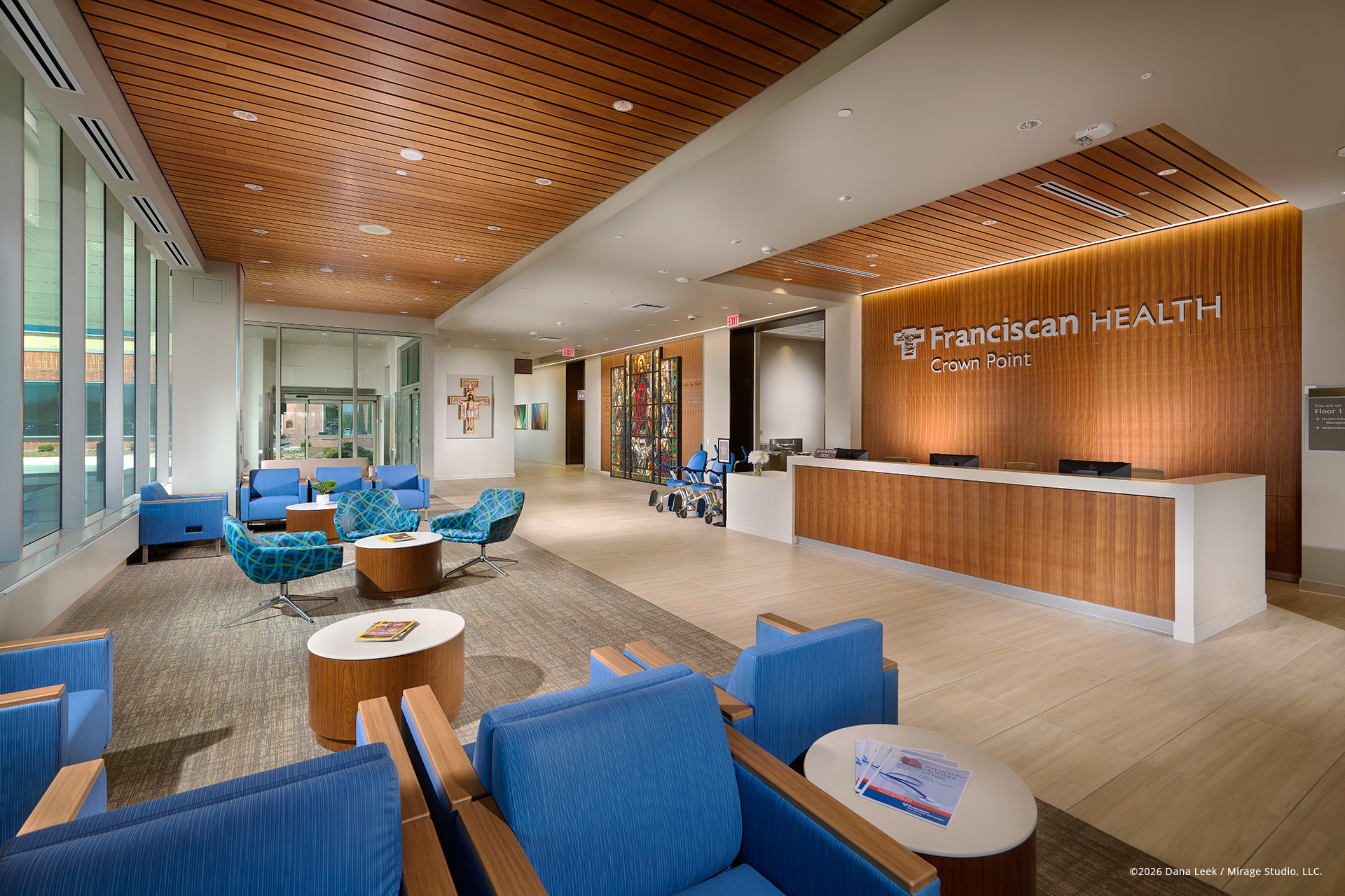 Contemporary commercial lobby interior with wood ceiling, large windows, and blue lounge furniture