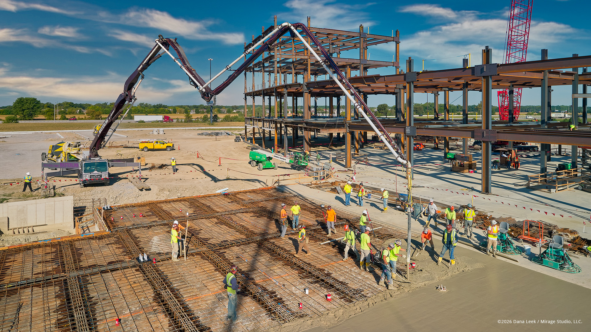 Aerial drone photograph of FHCP hospital construction site during concrete slab pour with crews and equipment visible.