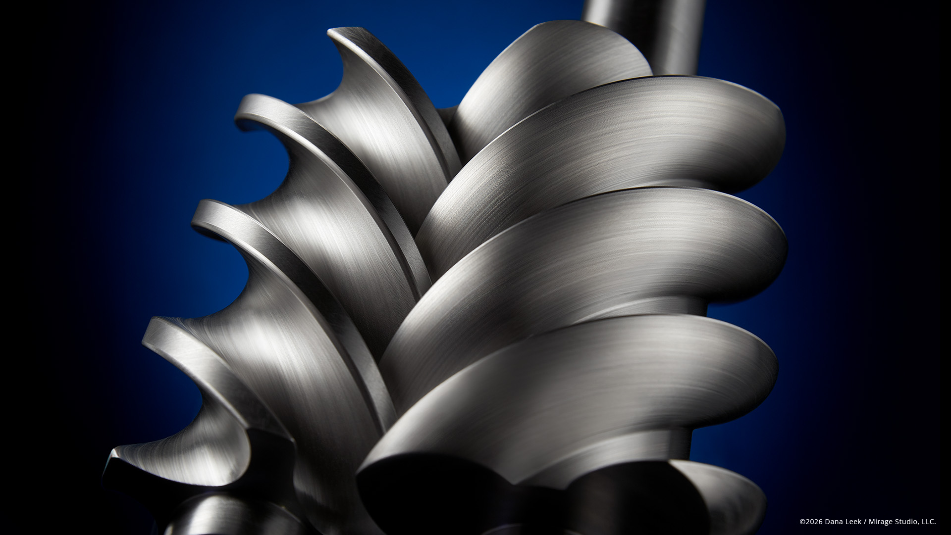 Studio product photograph of Vanair rotary screw air compressor rotors on blue background.